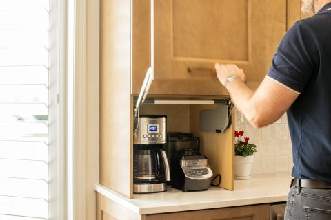 Greenville kitchen appliance garage with light-toned wood cabinetry, parallel lift-up door mechanism, coffee maker, and blender by Tekton Builds.