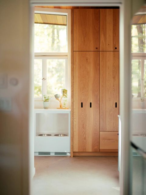 Greenville interior with light wood cabinetry, white built-in unit with pet feeding bowls, and under-cabinet lighting by Tekton Builds.